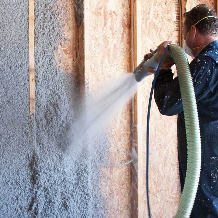 Legacy Roofing employee blowing insulation for home insulation services